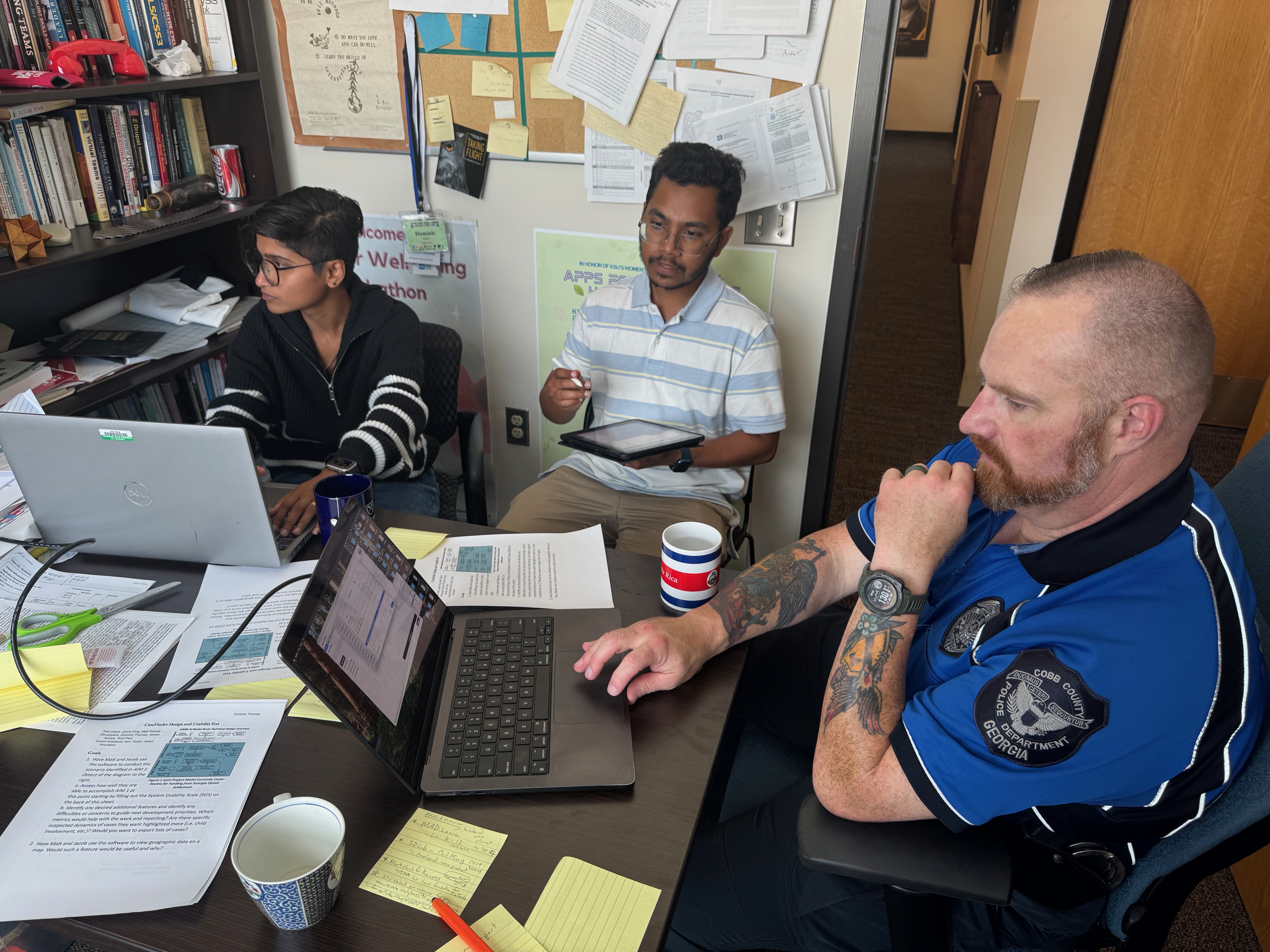 Police officer testing new software: Officer Jacob King with Adnan Azmee and Soni Paul in Prof. Thomas' office.