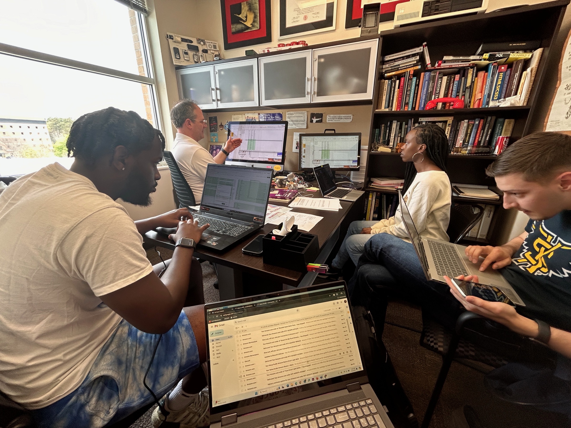Dominic Thomas working with student researchers on laptops in his office
